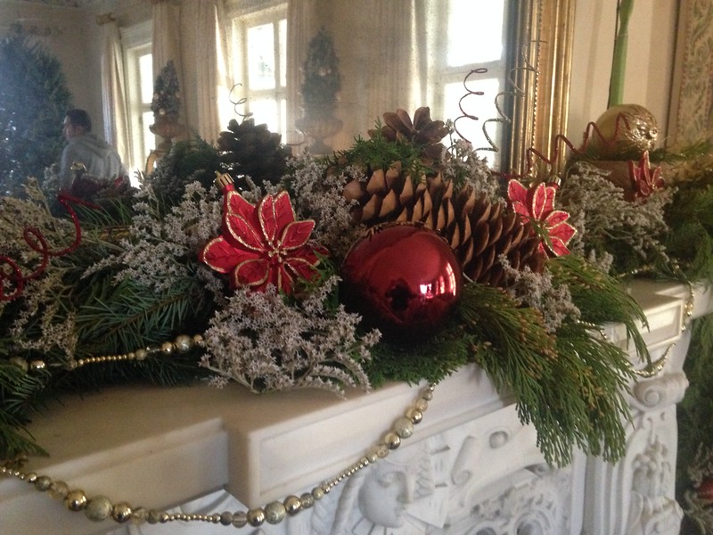 Christmas arrangement on fireplace mantle with evergreen leaves, pinecones, and ornaments